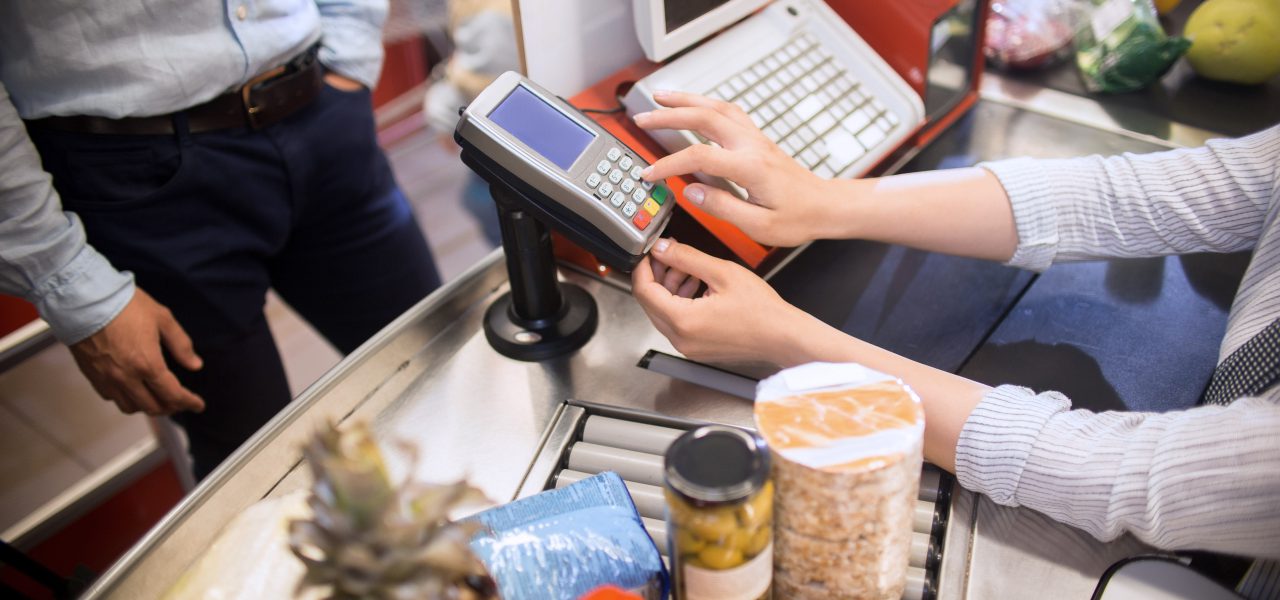 High angle closeup of cashier entering price to paying terminal at cash desk in supermarket